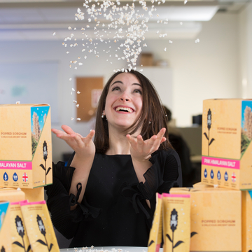 Lil Pop founder throwing little popcorn up in the air surrounded by Lil Pop packaging