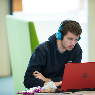 Student wearing headphones and studying at laptop