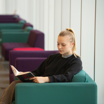 Student sitting on a chair reading a book