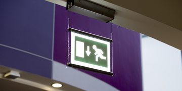 Green fire exit sign hanging from ceiling