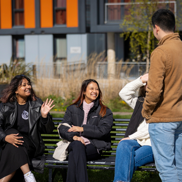Three students on a bench chatting outside Bainfield student accommodation