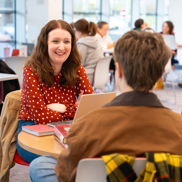 Two students in discussion over a table in the library