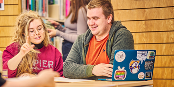 Two students working together with laptops
