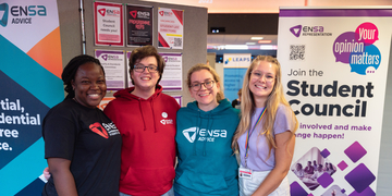 Four reps from the Edinburgh Napier Students' Association (ENSA) standing in front of student support banners