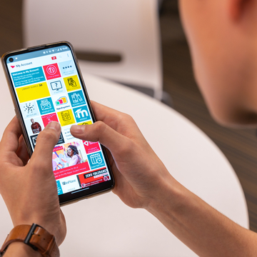 Student holding a mobile phone which displays the Edinburgh Napier app