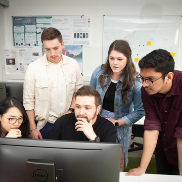 Image of students working together around a computer