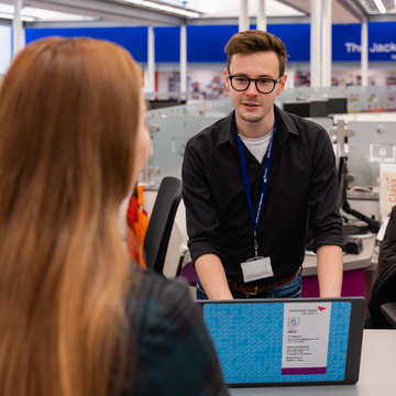 Student speaking to an Information Services staff member at the JKCC Helpdesk.