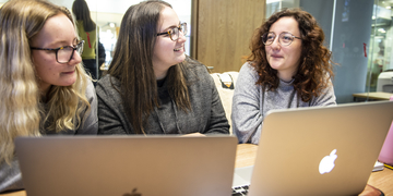 Three students working on laptops in study room