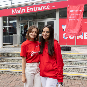 Two student ambassadors wearing red hoodies, standing outside Merchiston campus