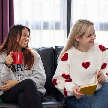 Two students reading books and drinking coffee in the lounge area of a student accommodation flat