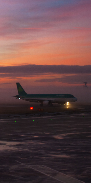 Sunset at an airport, with a plane on the runway in the background