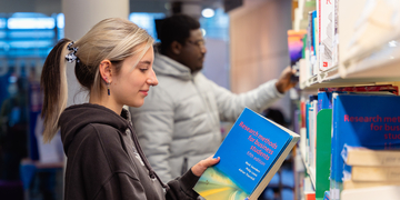Student looking at a book from the bookshelf in Craiglockhart Library