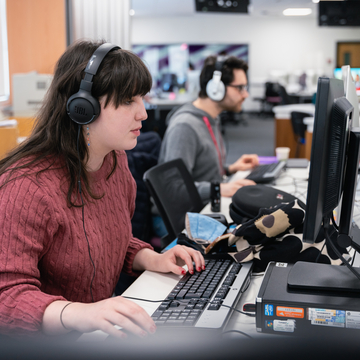 Student working at computer with headphones on