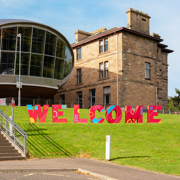 Patterned red 'Welcome' letters on lawn outside Craiglockhart campus