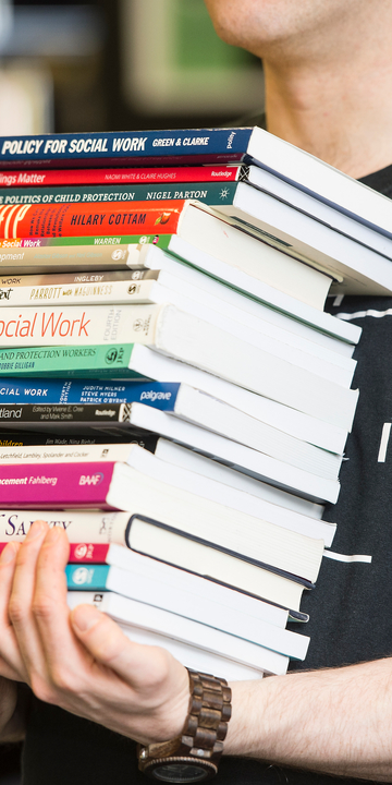 student carrying pile of books