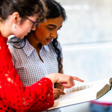 Students in Craiglockhart Library looking at a book