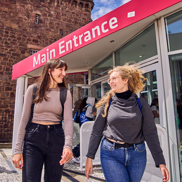 Two students walking in front of the main entrance at Merchiston campus
