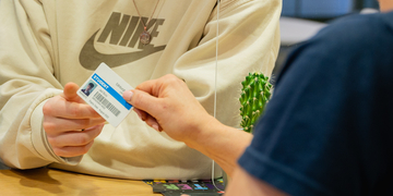 Member of staff at helpdesk handing over a student card to a student