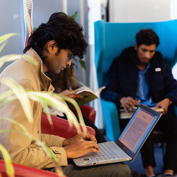 Students sitting in a common area working on their laptops