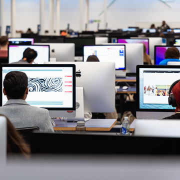 A row of students working on computers in one of the computer suites on campus
