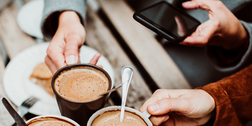 Students holding coffee cups and using a mobile phone