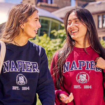Two students wearing blue and red Edinburgh Napier branded hoodies with the University crest