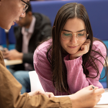 Two students looking over notes together, one of them holding a pencil