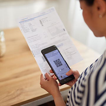Student holding a funding document and scanning a QR code on the page from their phone