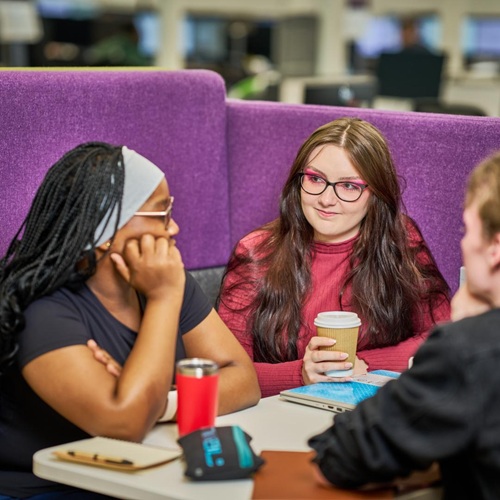 Students sitting at a table talking and drinking coffee