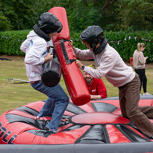 Two students playing on inflatable gladiator style game