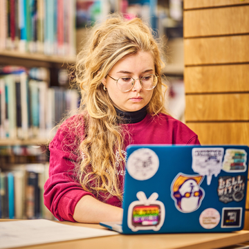 Student sitting in library area working at a laptop