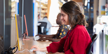 Side-on view of student working at a bank of computers on campus