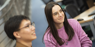 Two students smiling while listening to somebody talk