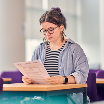 A student sitting in an examination room, looking at the exam paper