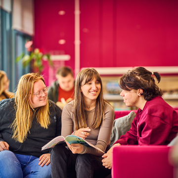 A group of students sitting in a study space, talking together and reading notes