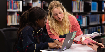 Two students sitting studying with a laptop