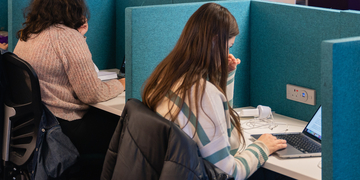 Students working on laptops in individual study booths