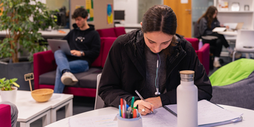 A student working with a notebook and pencil in a study area
