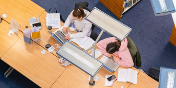 Birds-eye view of students studying with laptops in the library