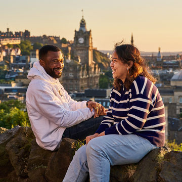 Two students sitting in front of a view of Edinburgh skyline, with Edinburgh Castle in the background