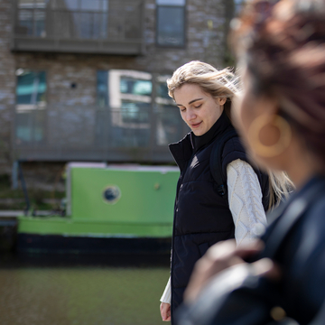 A group of students walking together next to a canal, with a canal boat in the background