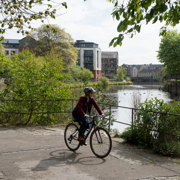 Student cycling bike on a path alongside canal