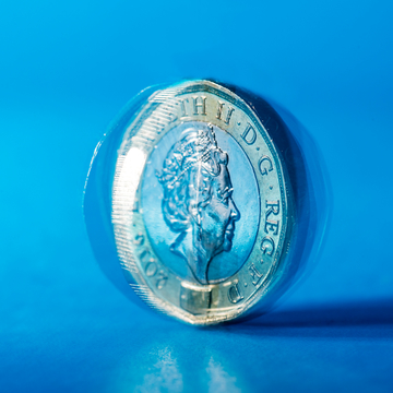 Pound coin spinning with a blue background