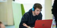 Student with headphones working at laptop