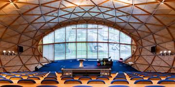 Inside of large lecture theatre with rows of seating and windows in the background