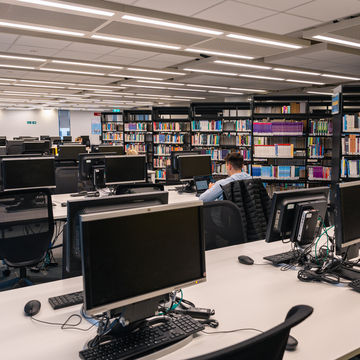 Sighthill Learning Resource Centre - Student at a computer next to Library bookshelves