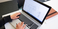 Hands typing on a laptop