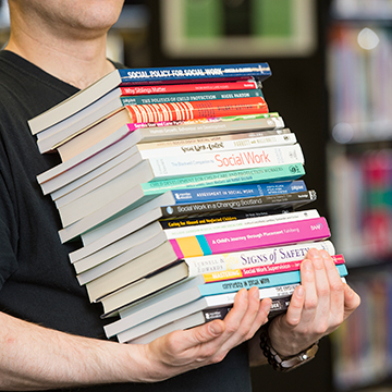 Person carrying stack of books