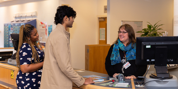 Students talking to a member of staff at Library helpdesk