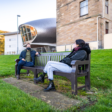 Students with masks sitting socially distanced on bench outside Craiglockhart campus